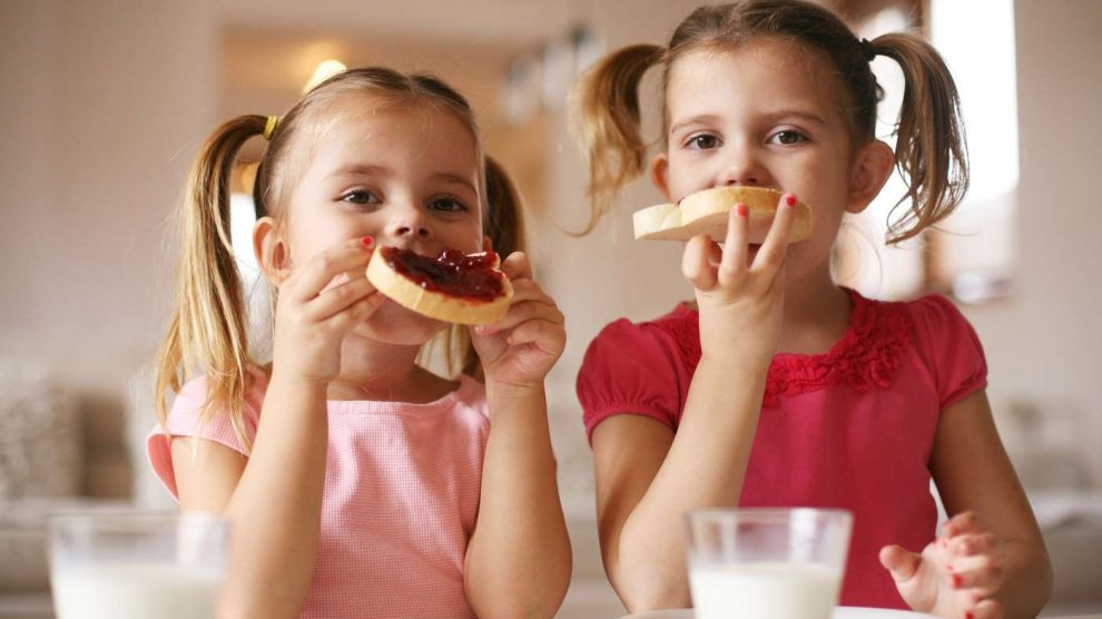 Két kislány lekváros kenyeret reggelizik