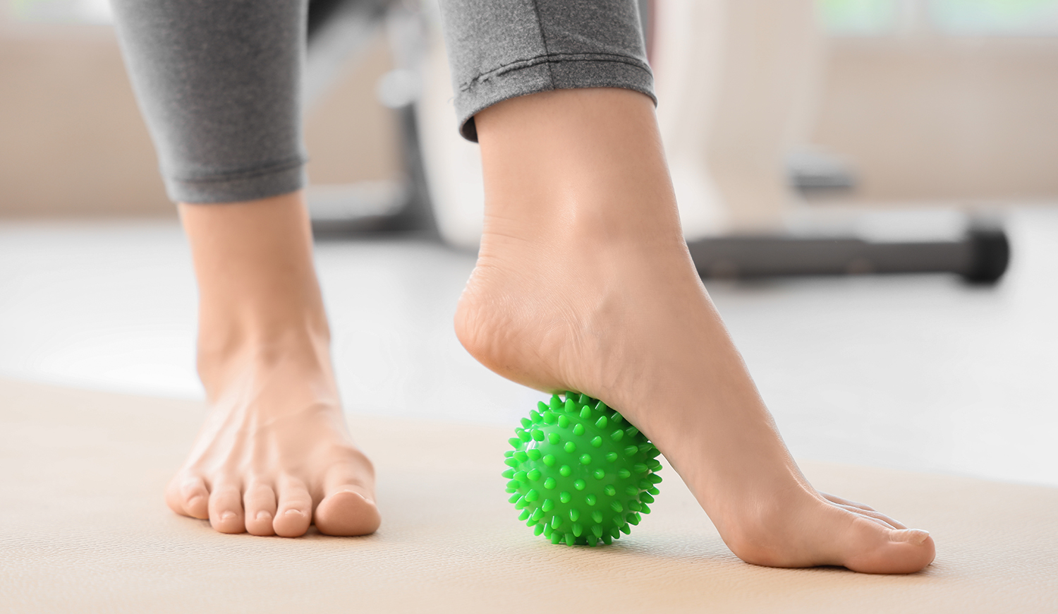 fiatal nő masszírozza a lábát labdával