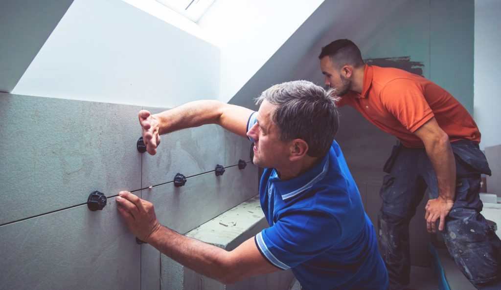 burkolók teszik fel a csempét egy fürdőszobában