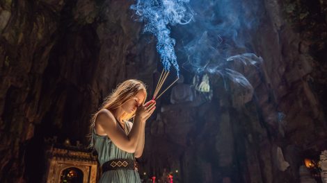 Fiatal nő imádkozik a kezében füstölővel