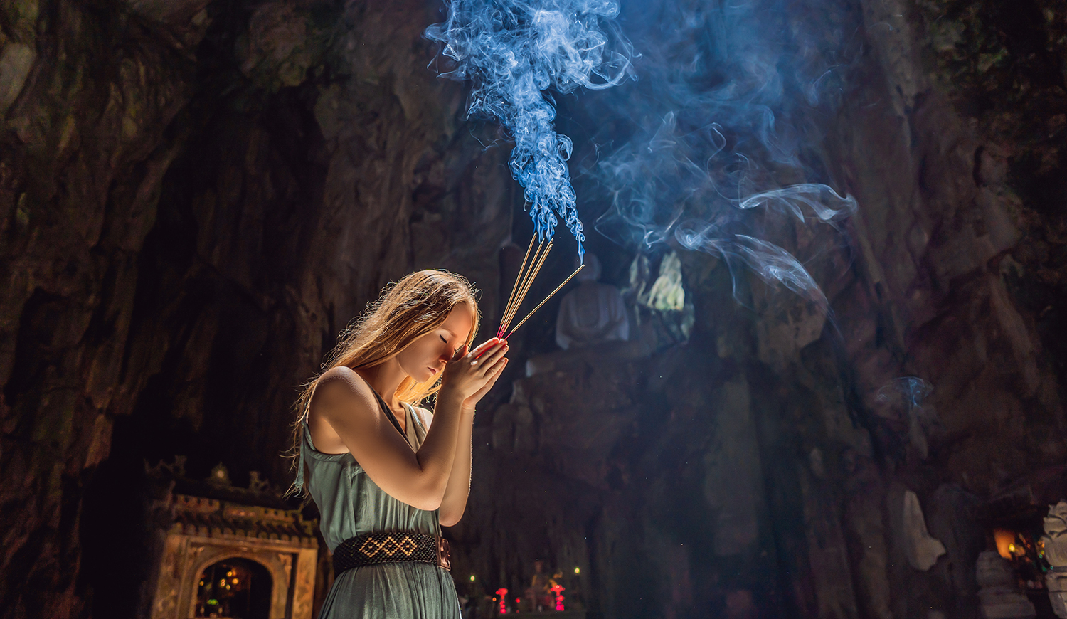 Fiatal nő imádkozik a kezében füstölővel