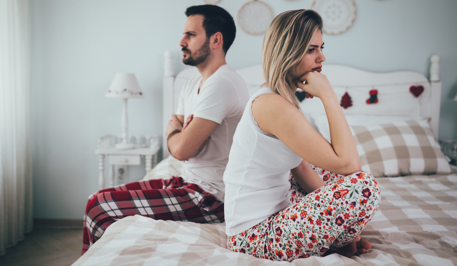 férfi és egy nő háttal ül egymásnak az ágyon