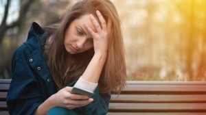 aggódó nő nézi a mobiltelefonját