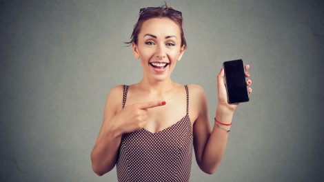 vidám nő mutatja a mobiltelefonját