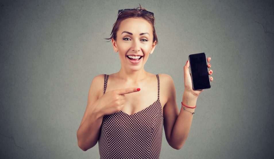 vidám nő mutatja a mobiltelefonját