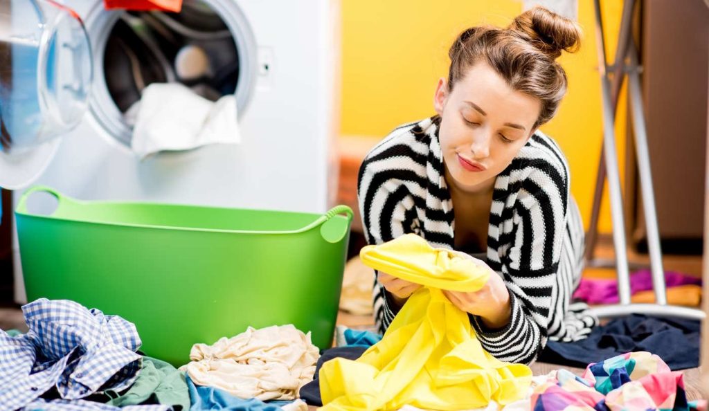 Nő nézi a mosás után a foltot a ruhán