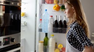 nő áll a nyitott hűtő előtt