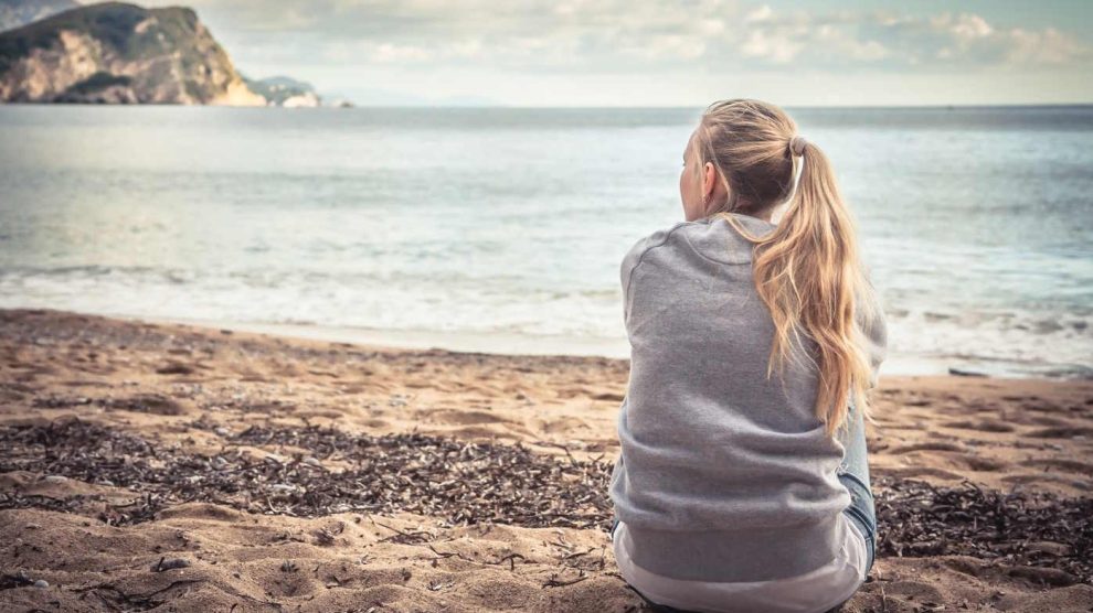 nő egyedül ül a tengerparton