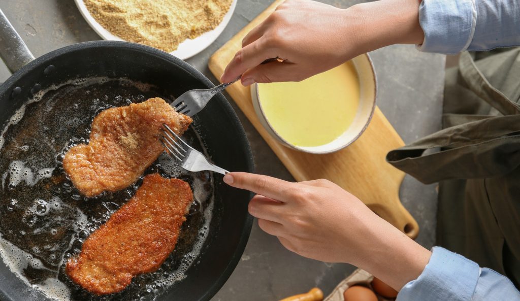 nő rántott húst süt bő olajban