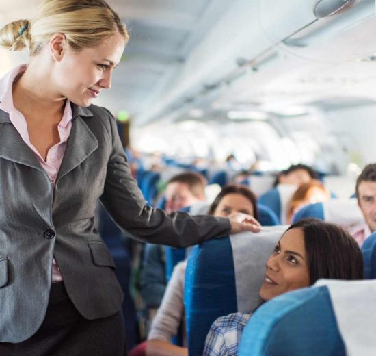 Légiutas-kísérő kedvesen mosolyog az utasokra a repülőn