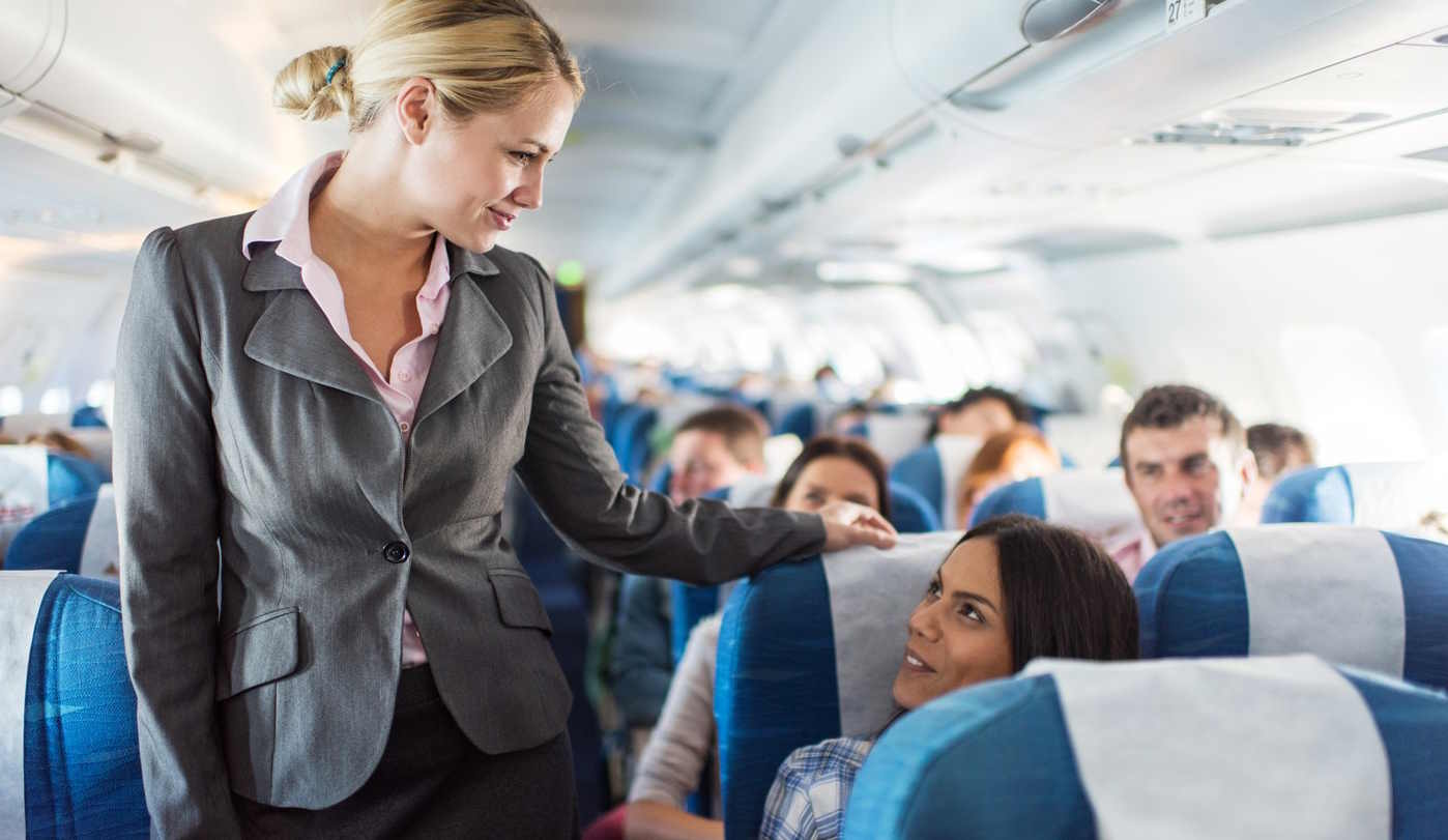 Légiutas-kísérő kedvesen mosolyog az utasokra a repülőn