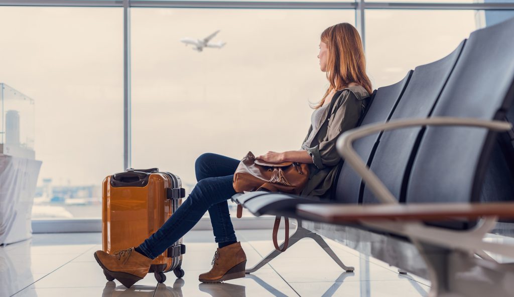 repülőtéren nő várakozik a beszállásra a poggyászával