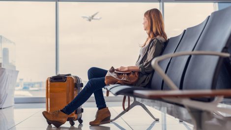 repülőtéren nő várakozik a beszállásra a poggyászával