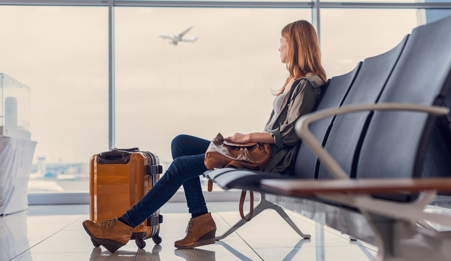repülőtéren nő várakozik a beszállásra a poggyászával