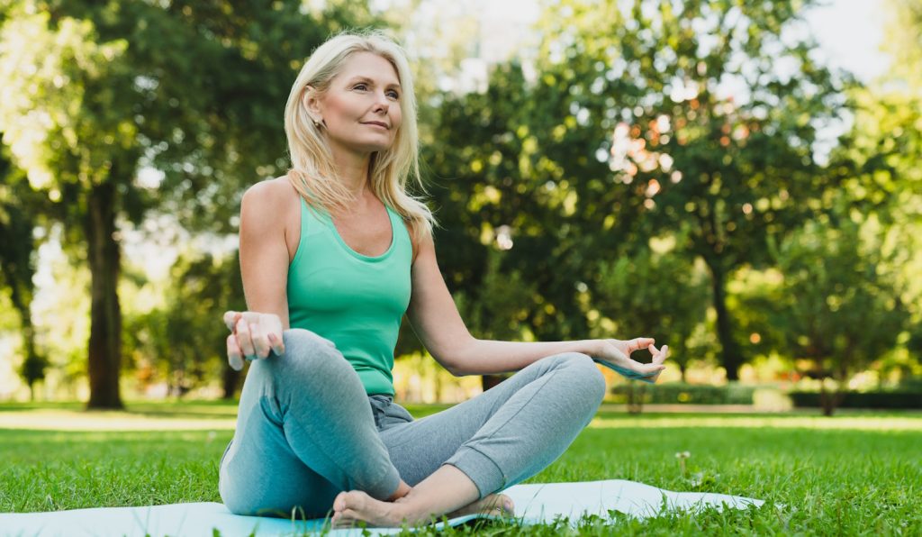 csinos idős hölgy jógázik a parkban