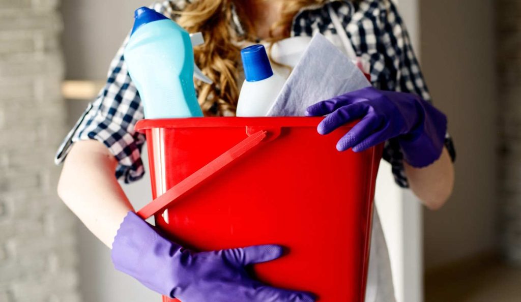 nő tisztítószerekkel a kezében
