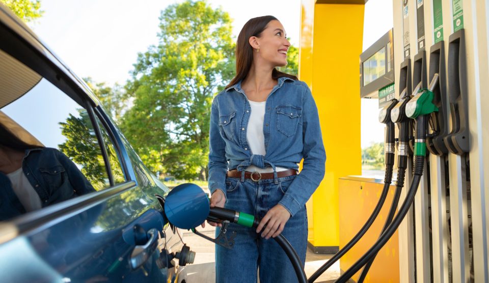 csinos nő örömmel tankol a benzinkúton