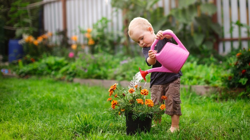 tavasszal a kertben büdöskét locsol egy kisfiú cuki fotó