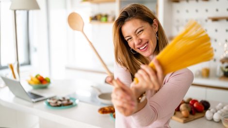 vidám fiatal háziasszony tésztát főz a konyhában