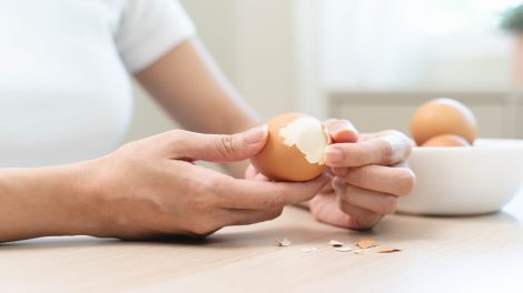 nő tojást pucol kézzel a konyhában húsvétra