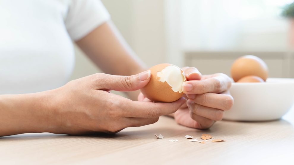 nő tojást pucol kézzel a konyhában húsvétra