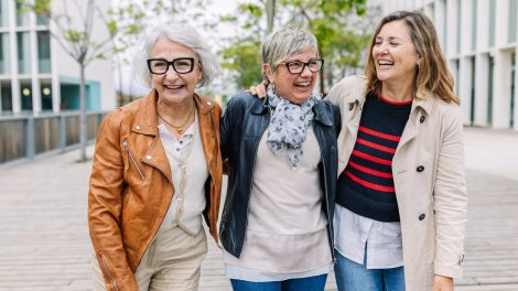 „Három nyugdíjas korú nő nevetve sétál együtt a szabadban. Hatvanas éveikben járó barátnők egy kis csoportja beszélgetve, jókedvűen élvezi egymás társaságát egy városi utcán. Az időskori barátság pillanata.”