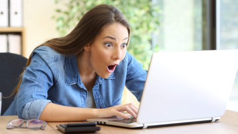 Nő nézi a laptopját és nagyon örül