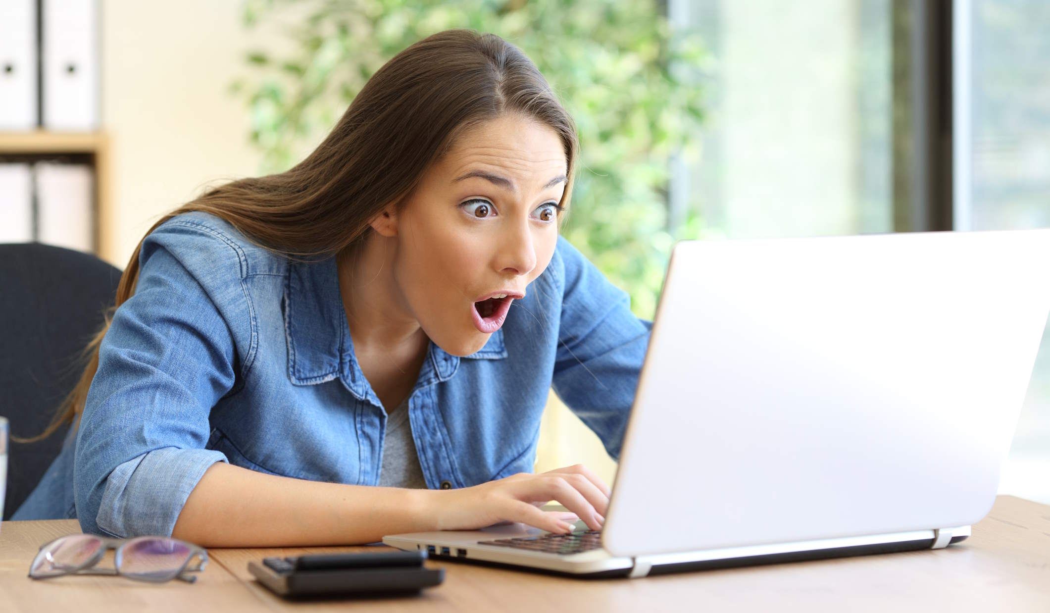 Nő nézi a laptopját és nagyon örül
