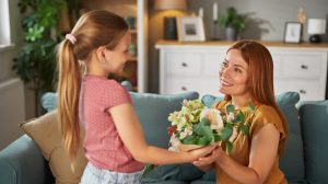 Kislány virágot ad ajándékba az édesanyjának