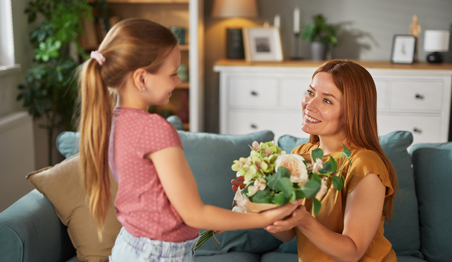 Kislány virágot ad ajándékba az édesanyjának