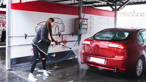 nő kézi autómosoóban mossa a piros autóját