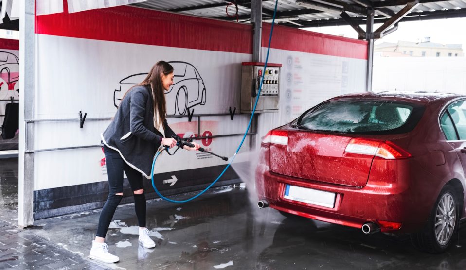 nő kézi autómosoóban mossa a piros autóját