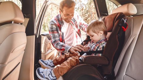 apuka autós gyerekülésbe teszi be a kisfiát a kocsiban
