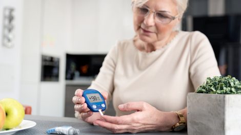 Egy idős hölgy méri a cukrát