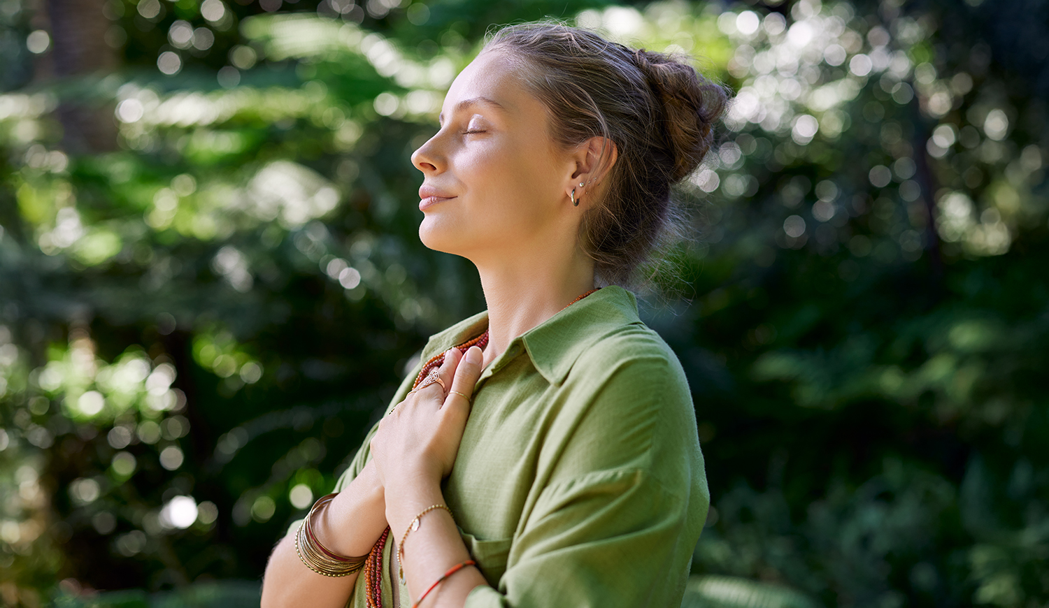 Egy nő csukott szemmel, mellkasára tett karral gyakorolja a tudatos jelenlétet