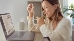Fiatal nő az interneten rendelt ékszerrel a kezében laptop előtt