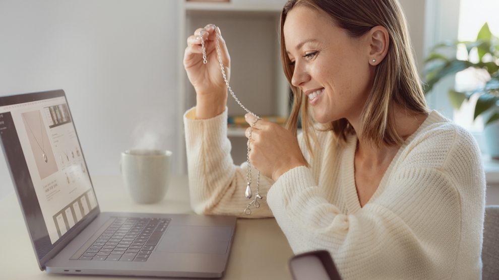 Fiatal nő az interneten rendelt ékszerrel a kezében laptop előtt