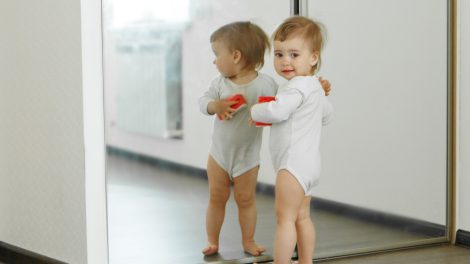 kisbaba áll a tükör előtt