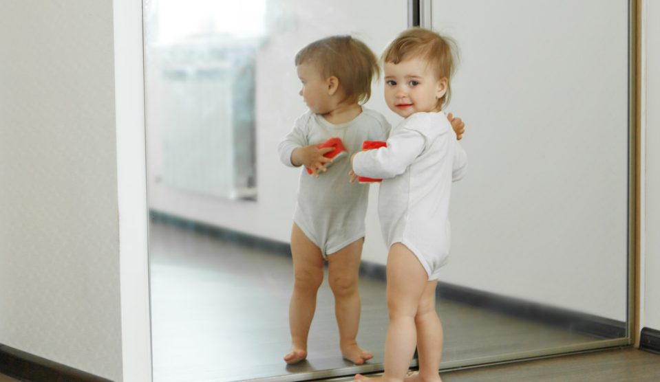 kisbaba áll a tükör előtt