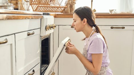 nő néz be a sütőbe egy vintage konyhában, hogy ksz van-e már a vacsora