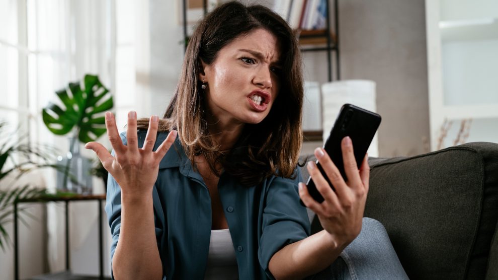 nő mérges a mobiltelefonjára, mert lassú