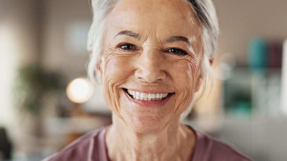 szép tiszta műfogsorral mosolyog egy idős nő