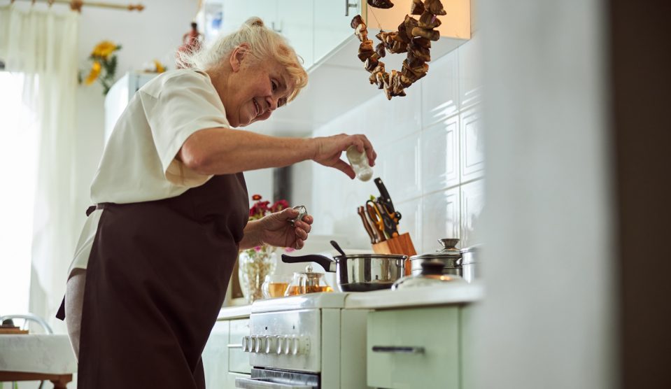 nagymama régi konyhában főz, sózza az ételt