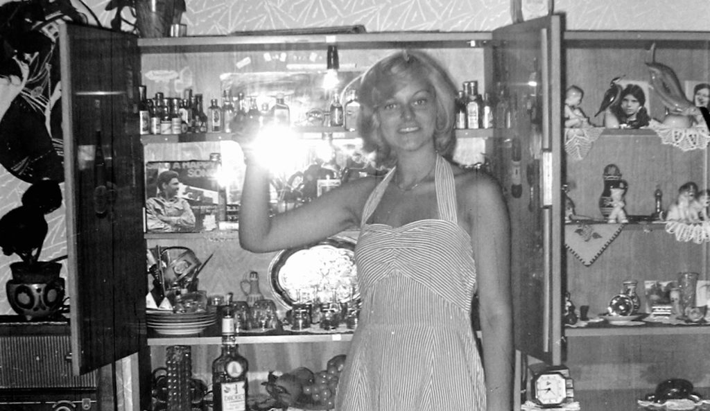 fiatal hölgy régi fekete-fehér fényképen a vitrinjét mutatja büszkén