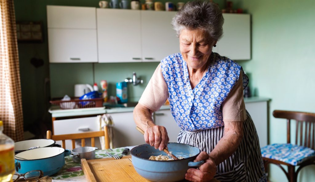 idős nagymama egy régi konyhában vidáman főz