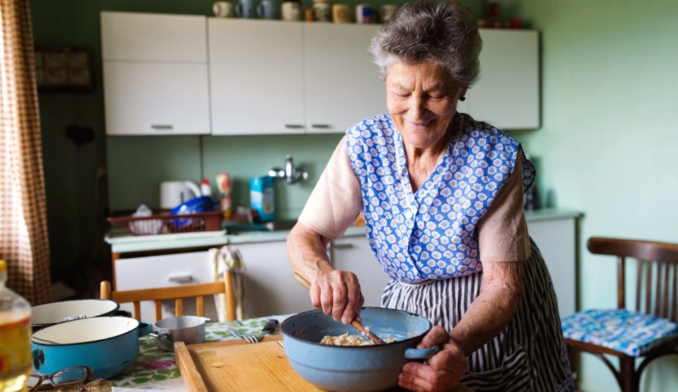 idős nagymama egy régi konyhában vidáman főz