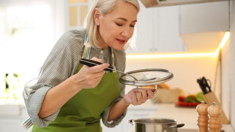szép nagymama a konyhában főz kóstolja a levest