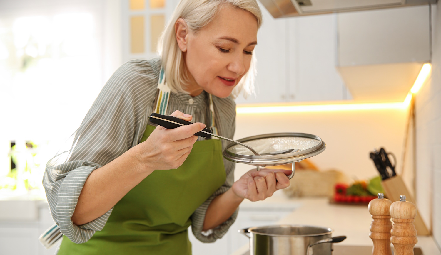 szép nagymama a konyhában főz kóstolja a levest