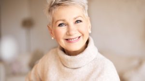 szép idős nő garbóban pasztel színek mosolyog