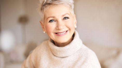 szép idős nő garbóban pasztel színek mosolyog